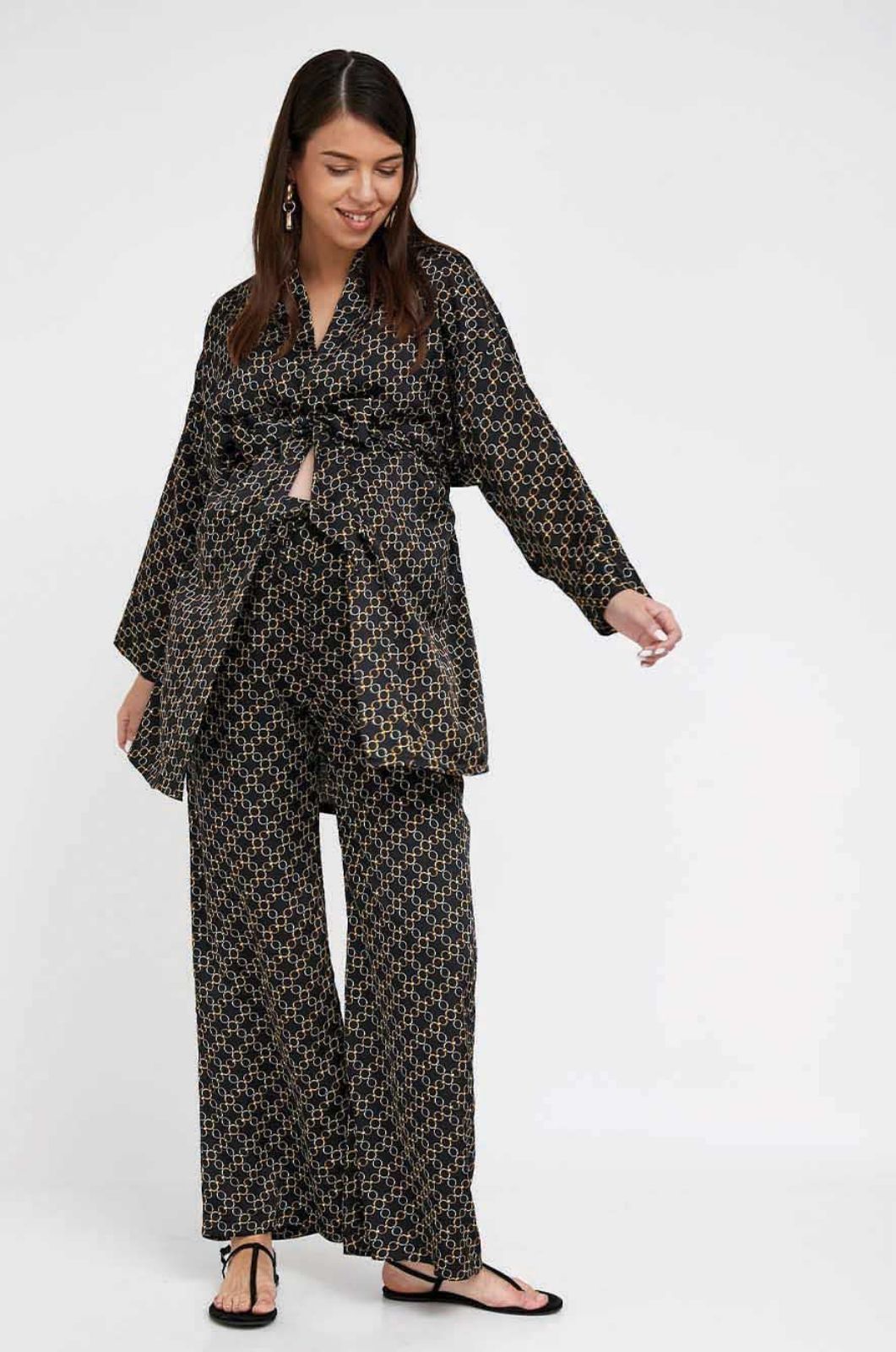 אישה לובשת קימונו סאטן להריון שחור מודפס של אבישג ארבל